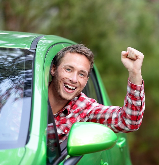 Young male driver looking at camera with arm raised cheering