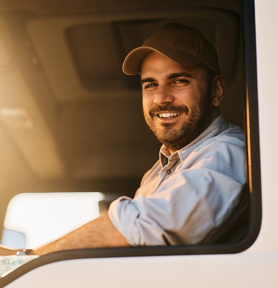 Happy truck driver sitting in vehicle cabin and looking at camera