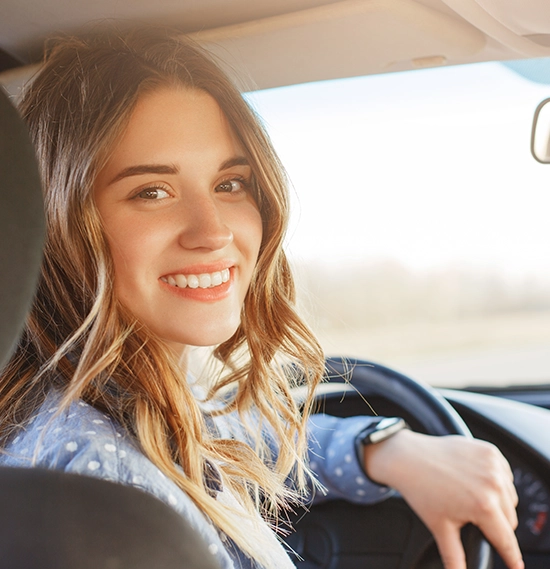 A close-up view of a female with a happy and positive expression as she sits in the driver's car seat
